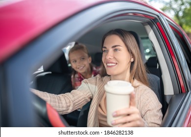 Lovely Motherhood. Smiling Mom Holding Coffee Cup, Driving With Her Daughter