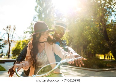 Lovely multicultural couple riding one bike together in a sunny day 