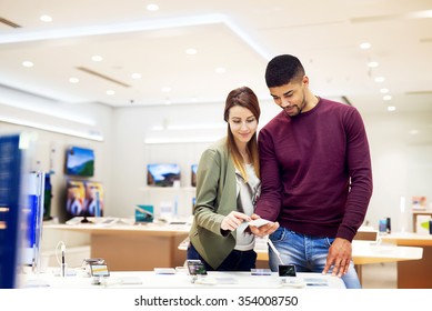 Lovely multiracial couple is at store and they are looking for a new mobile. Shallow depth of field. - Shutterstock ID 354008750