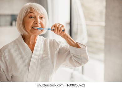 Lovely old lady cleaning teeth with toothbrush stock photo - Powered by Shutterstock