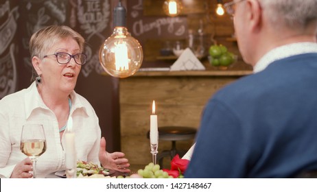 Lovely Old Lady Telling An Interesting Story To Her Husband Durring Lunch Time. Senior Couple. Man And Woman In Their Sixties.