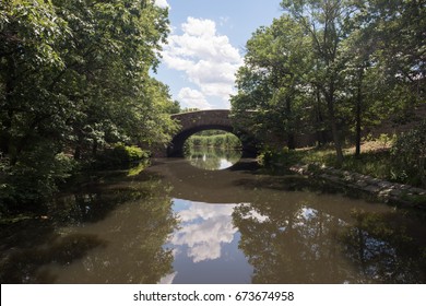 Lovely Old, Stone Bridge, Built In Colonial Times, In A Quaint New England Town, Over A Peaceful Waterway That Reflects A Clear Blue Sky.