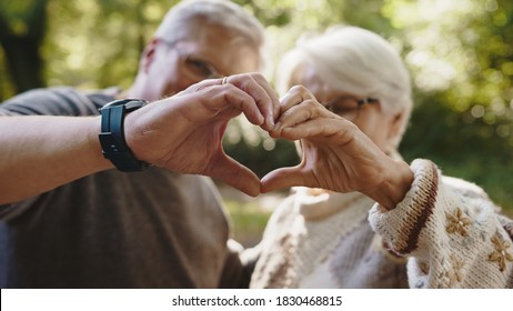 Lovely Older Retired Couple Making Heart With Their Hands And Looking At Each Other. Selective Focus. High Quality Photo