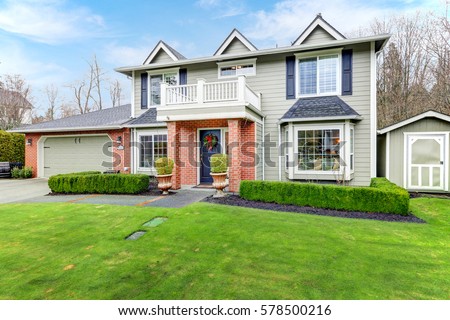 Lovely pale green Colonial home features red brick porch with columns, attached garage, shed and well manicured front yard. Northwest, USA