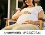 Lovely pregnant woman feeling baby kicks, looking happy.