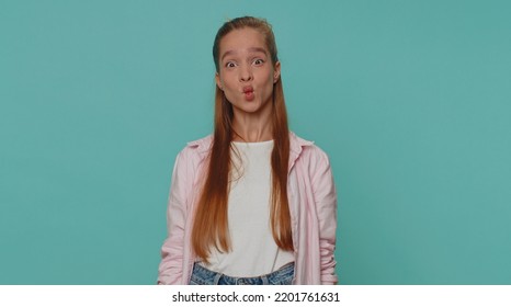 Lovely Pretty Funny Girl In Shirt Making Playful Silly Facial Expressions And Grimacing, Fooling Around, Fish Face. Young Stylish Female Child Kid Isolated Alone On Blue Studio Background Indoors