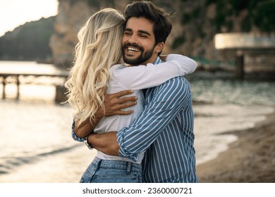 Lovely romantic couple hugging at the beach after handsome male proposed his girlfriend and she said yes.