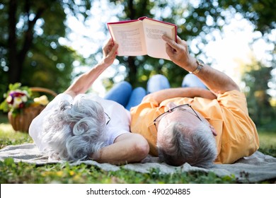 Lovely senior couple resting at park, reading a book - Powered by Shutterstock