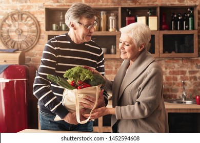 Lovely senior couple unpacking shopping bags with food in kitchen - Powered by Shutterstock