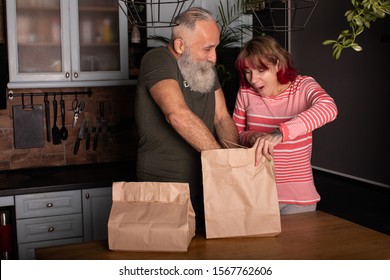 Lovely senior couple unpacking shopping bags with food in kitchen. - Powered by Shutterstock