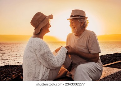 Lovely senior family couple hand in hand face the sea looking with love into each other eyes. Elderly retired man and woman enjoying vacation or retirement - Powered by Shutterstock