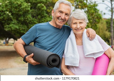 Lovely Senior Man And Old Woman Holding Yoga Mat For Exercising Outdoor. Aged Husband And Wife Ready For Yoga At Park. Active Healthy Retired Couple Looking At Camera Before A Postural Session.