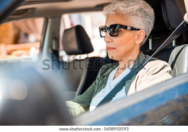 Lovely senior woman sitting on driver seat in auto\
stock photo