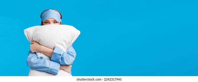 Lovely and sensual, tender cute redhead woman in nightwear, teen girl hugging pillow and smiling, squinting camera silly, like sleeping love bed, standing blue background delighted.