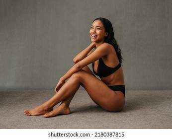Lovely smiling African American female sitting and showing her well toned body - Shutterstock ID 2180387815
