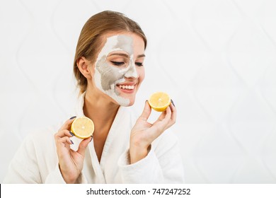 Lovely, smiling girl having fun with two halves of lemon, indoor shot in the white background - Powered by Shutterstock