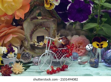 Lovely summer still life with funny snail, tiny bicycle, doll house, flowers and berries in the garden.   Greeting card, wedding or birthday concept. Vintage romantic background
