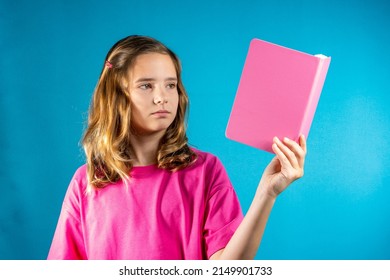 Lovely Teen Girl In Pink Is Reading A Book. The Concept Of School, Education, Self-study, Reading Books, Poetry And Creativity, Keeping A Diary, Romance Novels, Traditional Values.