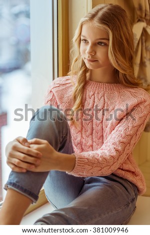 Lovely teenage girl sitting on the window sill in the room
