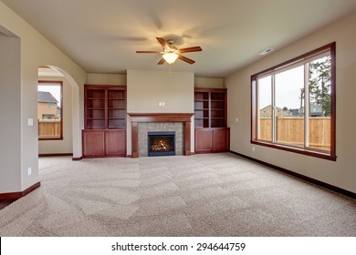 Lovely unfurnished living room with stained wood cabinets and fireplace.