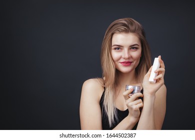 Lovely Woman With Natural Makup And Smooth Healthy Skin Holding Jars Of Beauty Products