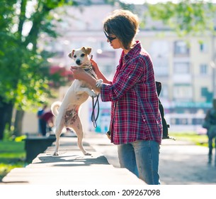 Lovely Woman In Sunglasses Walking In A City Park With A Dog