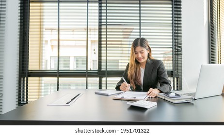 The Lovely Young Asian Accountant Enjoys Working On Computers And Calculators In The Office.