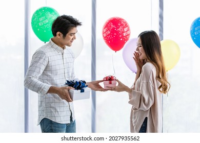 Lovely Young Asian Girl And Boy Couple Happy And Enjoy Exchange Gift Boxes To Other During Celebrate Sweet Ecstasy At New Year Party Of Colorful Balloon