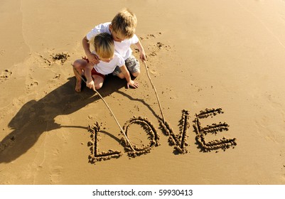 Lovely young brother and sister write words in the sand together