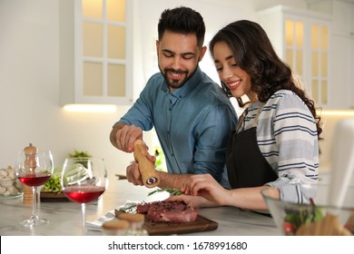 Lovely Young Couple Cooking Meat Together In Kitchen