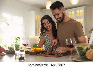 Lovely Young Couple Cooking Meat Together In Kitchen