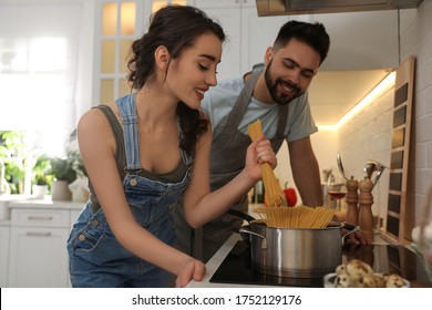 Lovely Young Couple Cooking Pasta Together In Kitchen