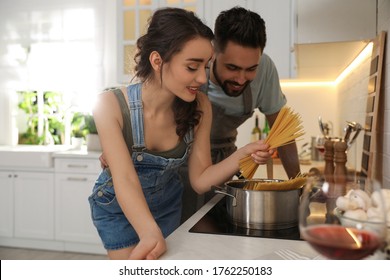 Lovely Young Couple Cooking Pasta Together In Kitchen