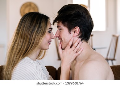 Lovely Young Couple Cuddling Smiling And Looking At Each Other On Comfortable Couch At Home