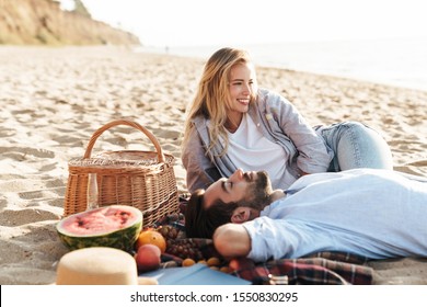 Lovely young couple having a picnic at the beach, laughing - Powered by Shutterstock