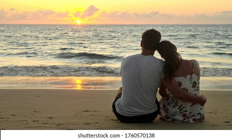 lovely young couple hugs sitting on empty ocean beach watching sunset at tropical resort in evening backside view copyspace - Powered by Shutterstock