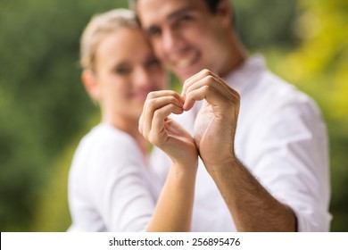 lovely young couple making heart with hands