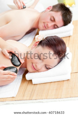 Lovely young couple receiving a back massage with hot stones in a spa center