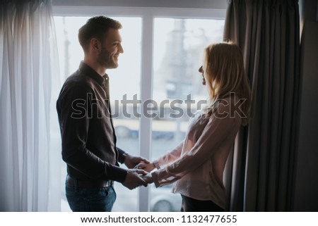 Lovely young couple standing by the window in the room