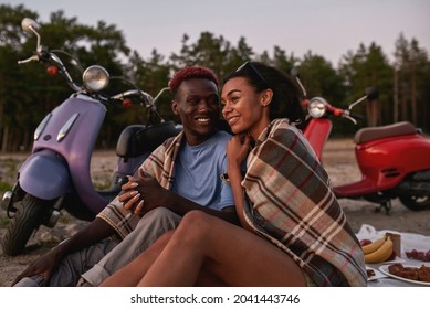 Lovely young diverse couple smiling, relaxing together on the beach covered with blanket in the evening. Romance, relationships, date concept - Powered by Shutterstock