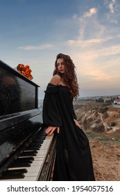 Lovely young woman near the piano with flowers and a glass on the background of the sea and rocks, the concept of a romantic date 