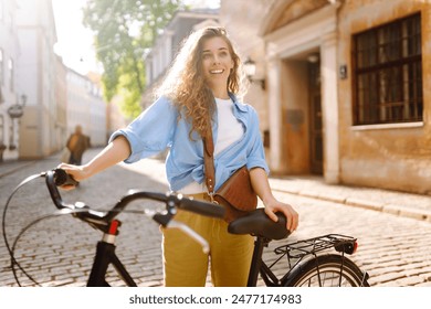 Lovely young woman posing with bike on the street of city, on sunny day. Active lifestyle. Eco transport. - Powered by Shutterstock