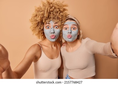 Lovely young women make grimace at camera keep lips folded apply beauty clay mask to reduce fine lines dressed casually isolated over brown background. Facial treatments and skin care concept - Shutterstock ID 2157768427