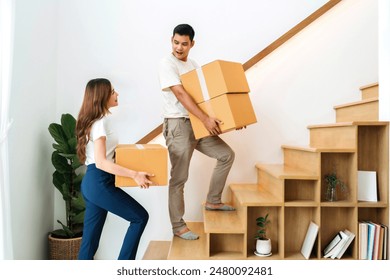 lover lifting box walking up stairs in new home. family together carrying cardboard box up next level of house. wife and husband help holding packaging box next floor relocating preparing new house. - Powered by Shutterstock