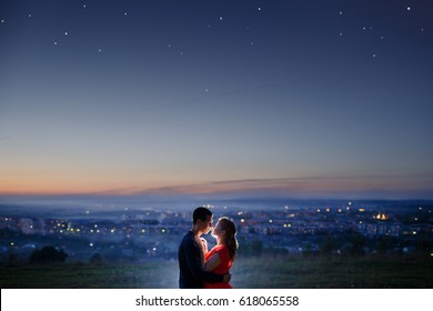 Lovers Against Background Of Night City, Starry Sky And Horizon. Concept Is Date On Roof, First Love