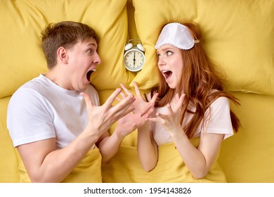 Lovers In Bed Looking Terrified As Hearing Alarm Clocks. Horrified Young Married Couple Overslept Work