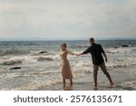 lovers and romantic newlyweds having fun on the seashore. couple running on the water. on a bright sunny day lovers dancing on the sea. girl wearing a beige dress. her hair styled