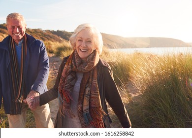 Loving Active Senior Couple Holding Hands As They Walk Through Sand Dunes - Powered by Shutterstock