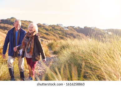 Loving Active Senior Couple Holding Hands As They Walk Through Sand Dunes - Powered by Shutterstock