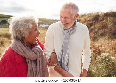 Loving Active Senior Couple Walking Arm In Arm Through Sand Dunes On Winter Beach Vacation - Powered by Shutterstock